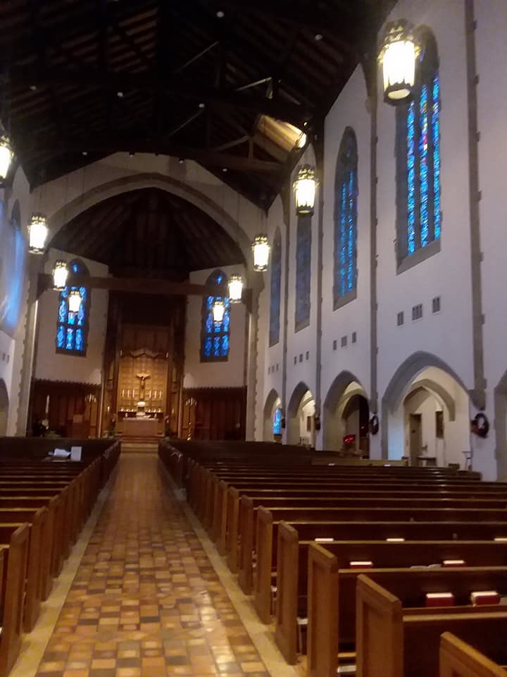 A view down the main chapel walkway towards the altar, there is very pretty blue stained glass windows visible on the right.