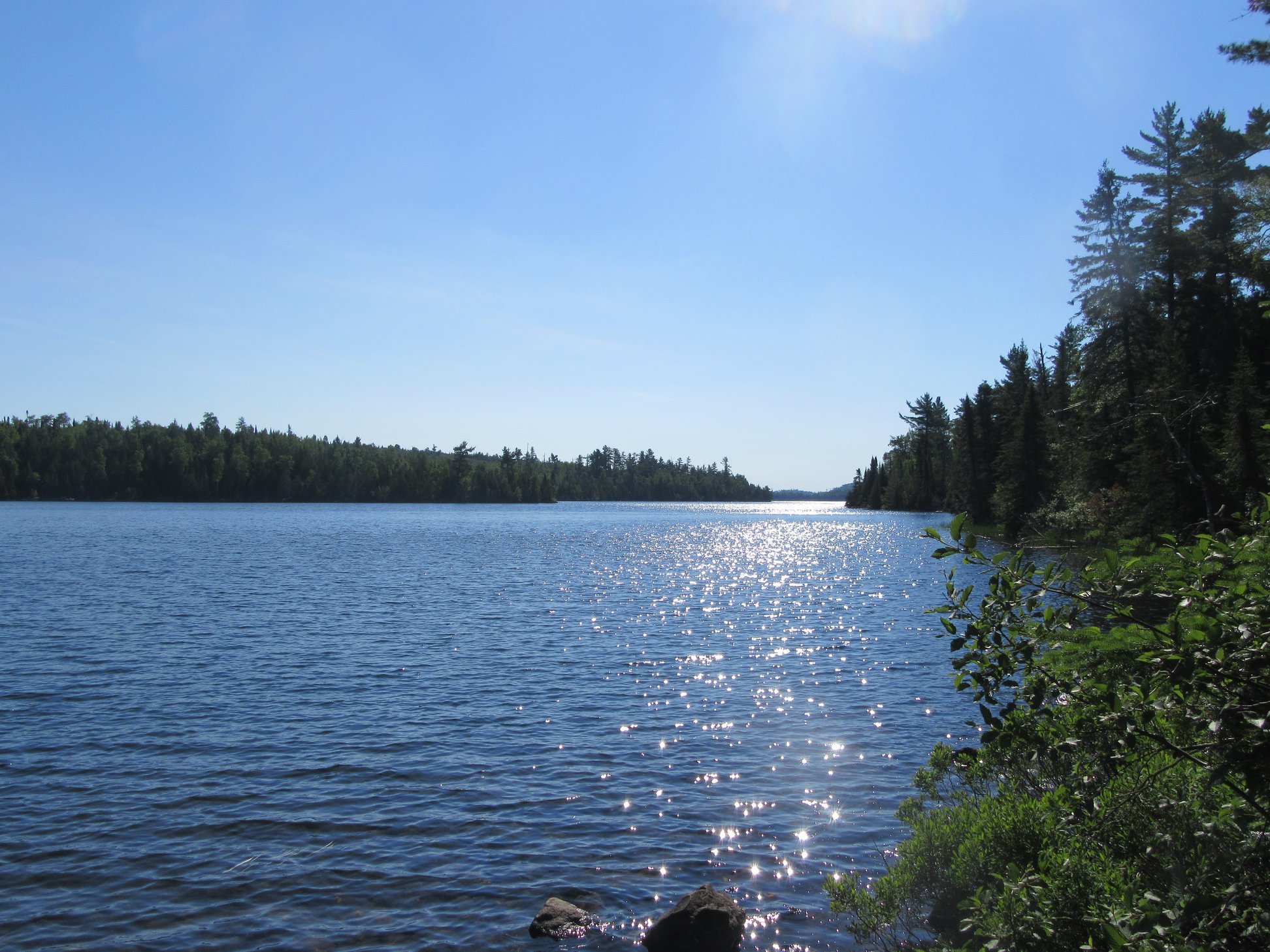 Canoer's back and vista of a calm northwoods lake.